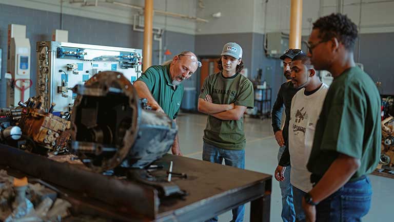 Photo of advisor and students working on an engine.