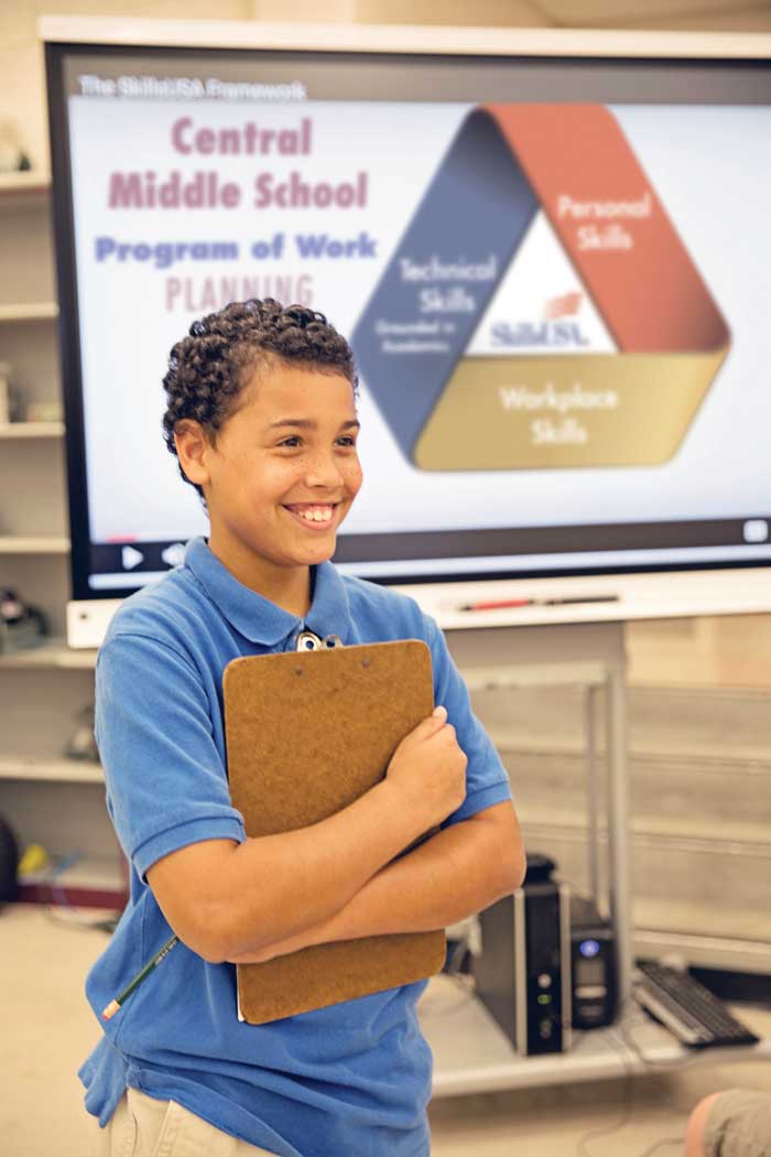 Photo of a smiling middle school student in front of the SkillsUSA Framework.
