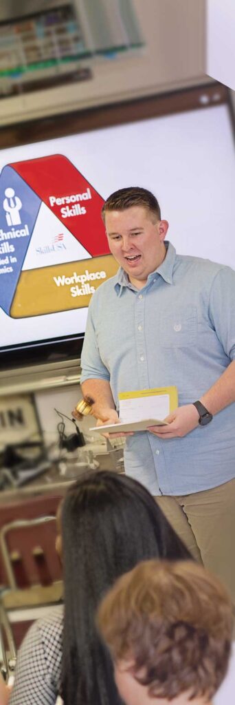 Photo of an instructor in front of the classroom with the SkillsUSA Framework behind him.