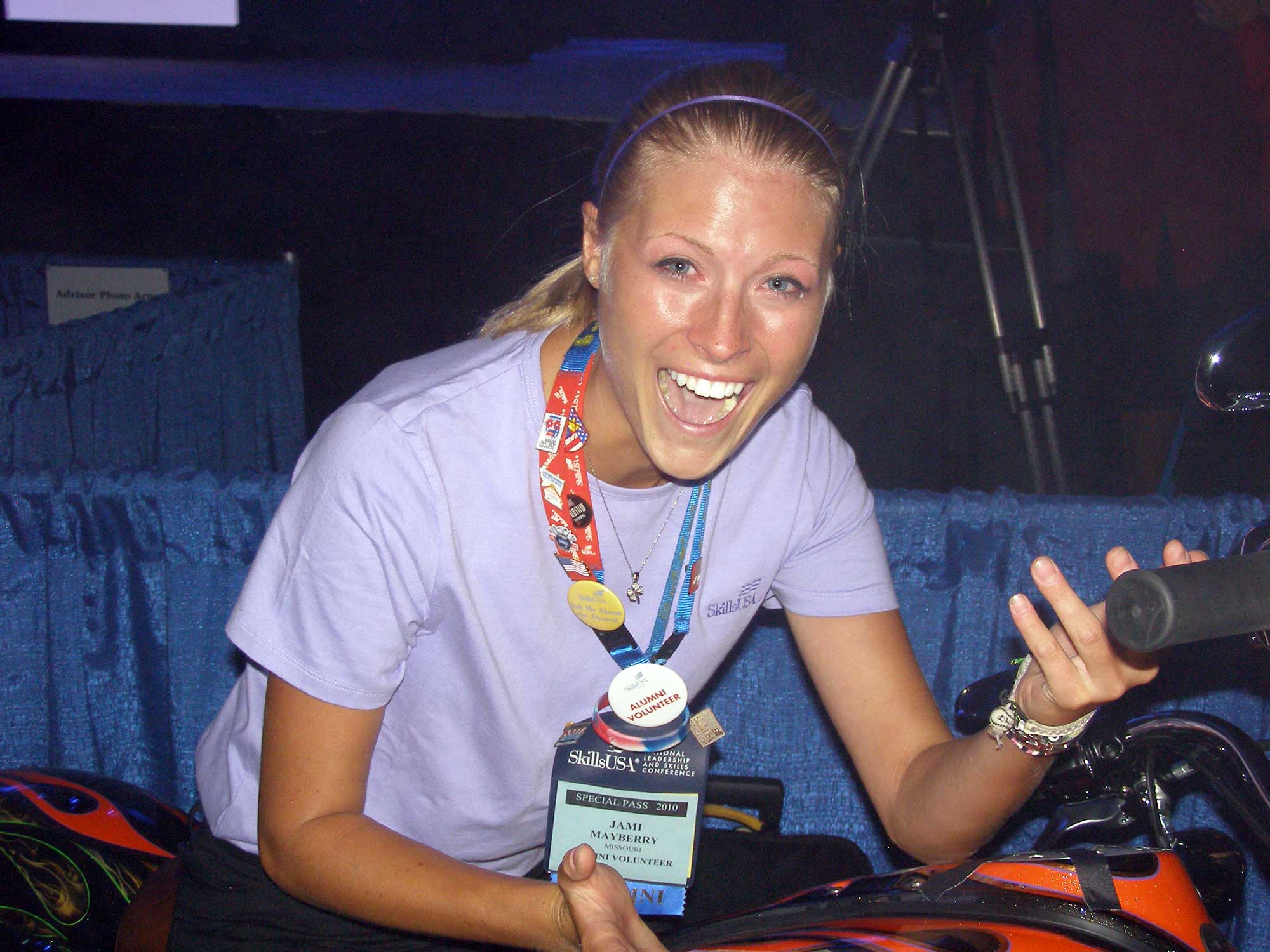 Smiling student sitting on a Harley Davidson motorcyle.}