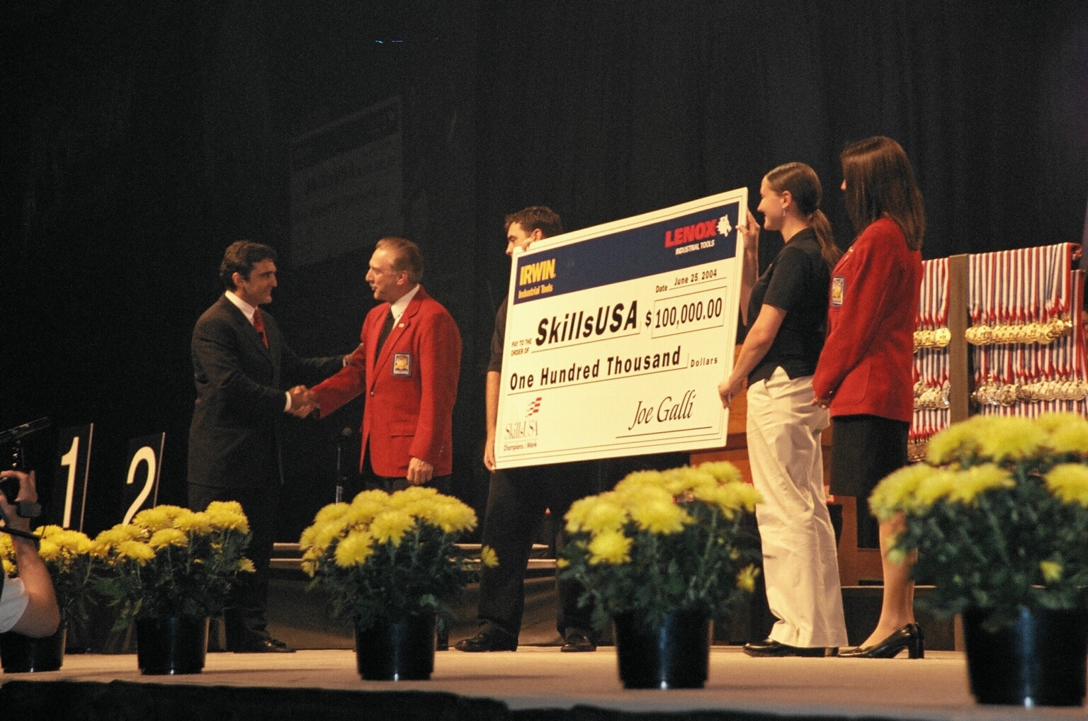 Irwin Tools CEO Joe Galli presents a 100,000 check on stage.}