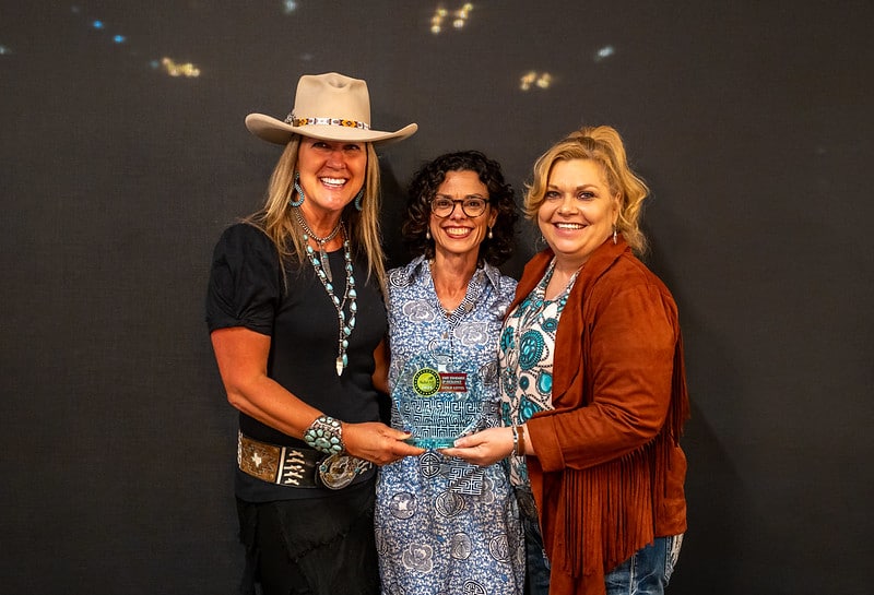 Chelle Travis presenting an award to Janie Wilcox and Shawna Reichert