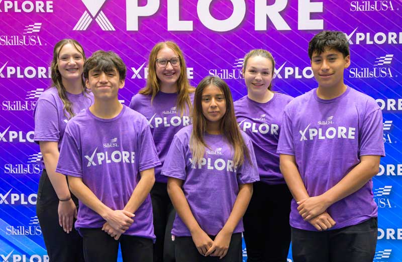 Six students posing in front of the Xplore backdrop