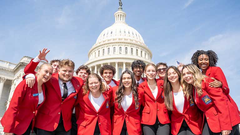 SkillsUSA National Officers in front of the U.S. Capitol building. They are pointing at the camera.