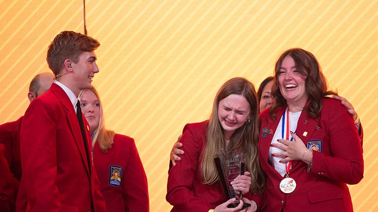 2025 Models of Excellence winners on stage reacting emotionally to the announcement.