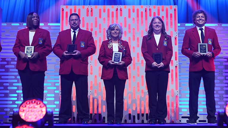 Five regional advisors of the year with their awards on stage at NLSC.