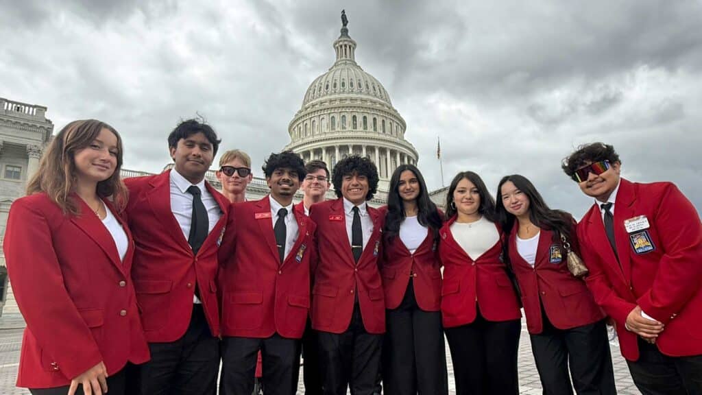 A group of 10 SkillsUSA students in red blazers posing in front of the U.S. Capitol Building.